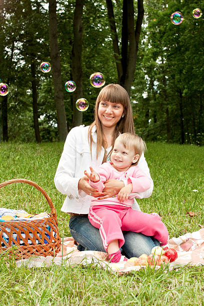 Mother with baby in the park looking at soap bubbles