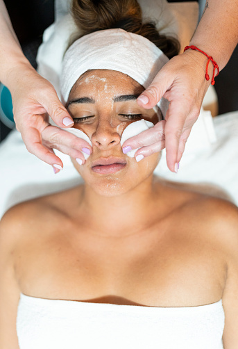 Top view of a relaxed woman receiving facial exfoliation in spa