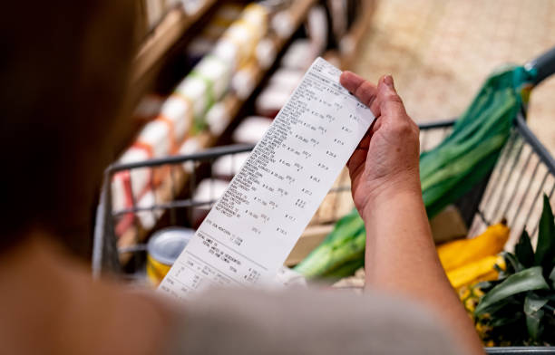 mujer mirando un recibo después de comprar en el supermercado - inflation fotografías e imágenes de stock