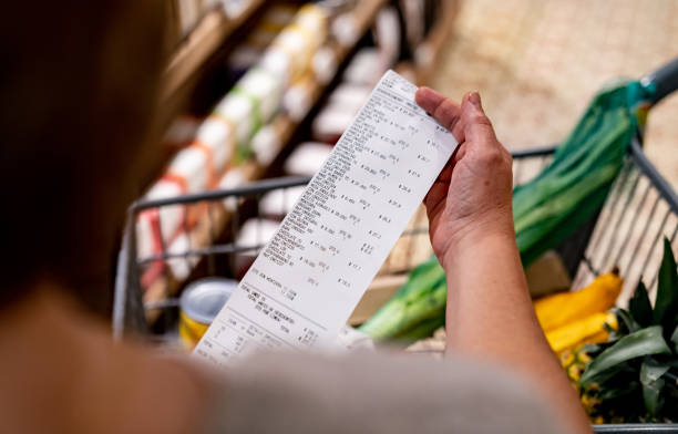 スーパーで買い物をした後、レシートを見る女性 - inflation ストックフォトと画像