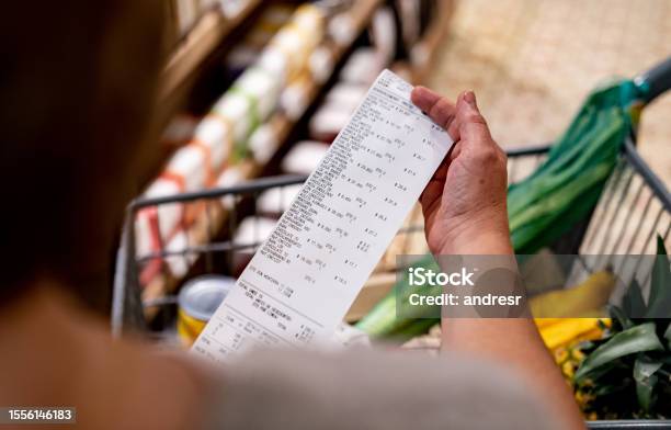Woman Looking At A Receipt After Shopping At The Supermarket Stock Photo - Download Image Now