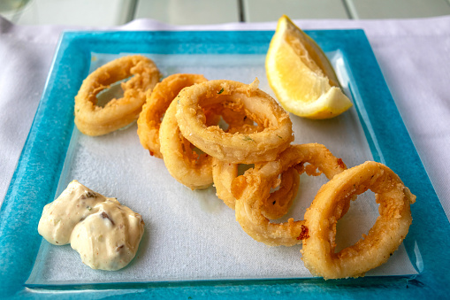 Fried calimari rings with a slice of lemon and a remoulade sauce.