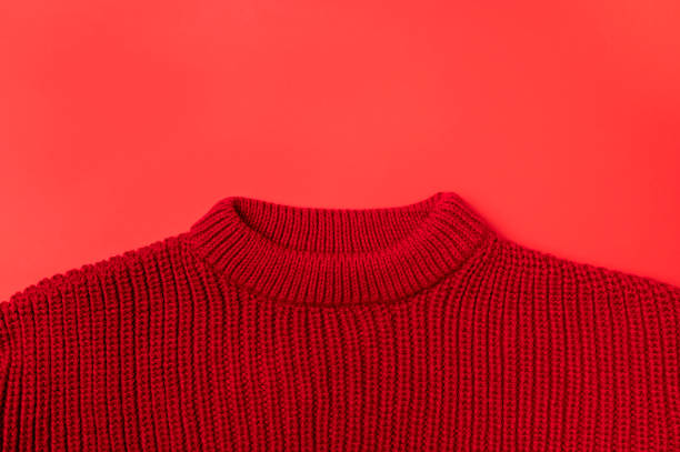 Red knitted sweater on red background top view with copy space. Texture of woolen cotton winter autumn cozy sweater, clothes. Knitted jumper, pullover, fashion. Sweater close-up