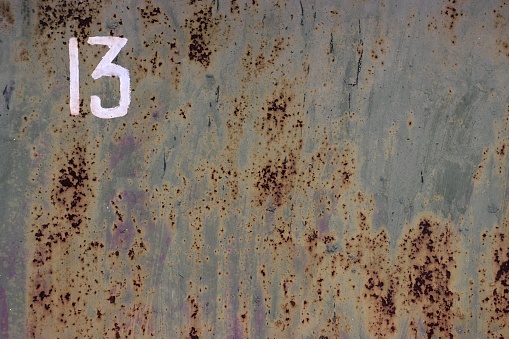 Image of an iron gate with clearly visible traces of rust and the number 13.