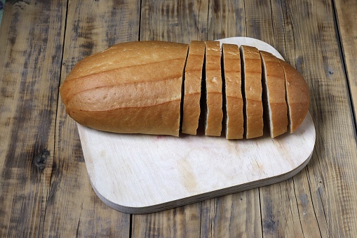 A loaf of bread is cut into pieces on a cutting board.