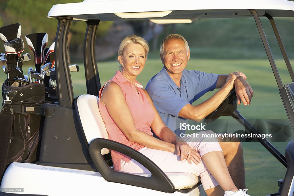 Senior Couple Riding In Golf Buggy Senior Couple Riding In Golf Buggy On Golf Course And Smiling Golf Stock Photo