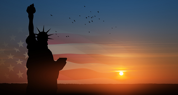 Statue of Liberty with American flag and flying birds on background of sunset sky. Close-up. Greeting card for Independence Day. USA celebration.