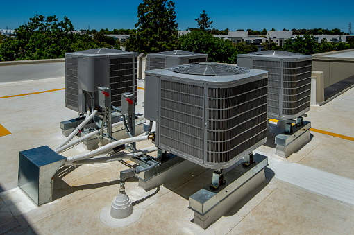 Set of four air conditioning units on a membrane roof.