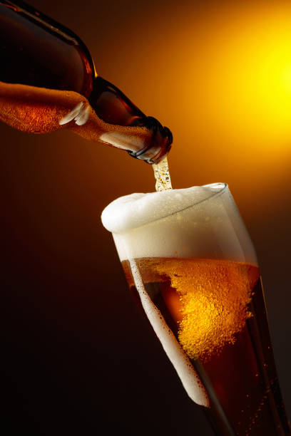 Pouring beer into a tall glass. stock photo