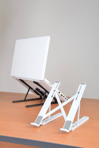 istock Standing laptop holder set up with notebook on desk 1556367864