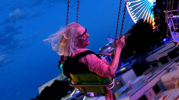 Laughing attractive woman flies over the changing lights of the fair.