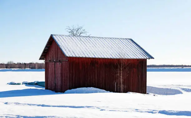 a small red barn in a sunny winter landscape