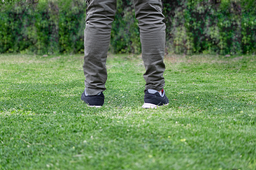 Man legs walking over green grass.