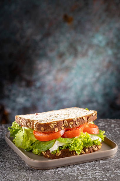 istock Delicious natural sandwich with lettuce, tomato, arugula and white cheese. 1556423895