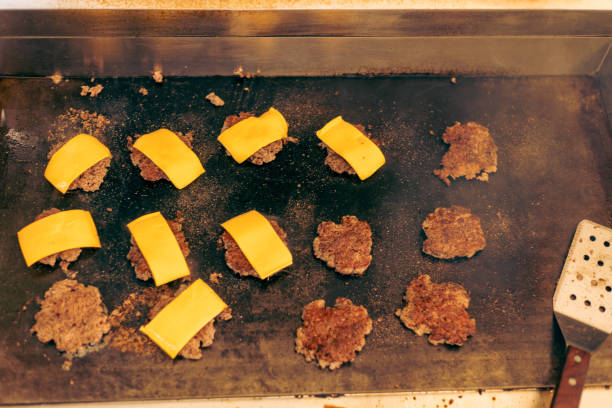 istock Minced Meat with Cheese for Hamburger on Flat Top Grill Outdoors. 1556457933