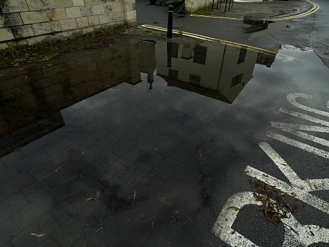 Reflection of building and sky in puddle.