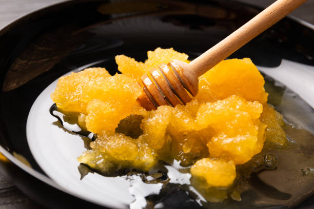 istock Crystallized honey and wooden dipper in a plate close-up 1556491016