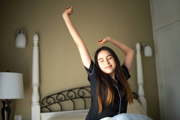 istock Young woman stretching after waking up in a bed at home 1556492573