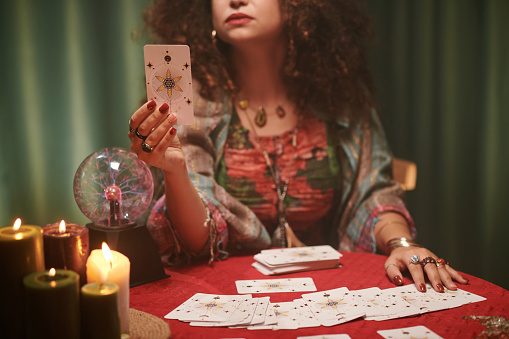 Gypsy fortune teller with glowing crystal ball on red velvet