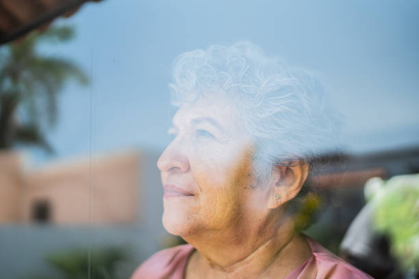 istock Senior woman contemplating through window at home 1556516545