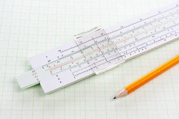Slide rule on squared paper with wooden pencil