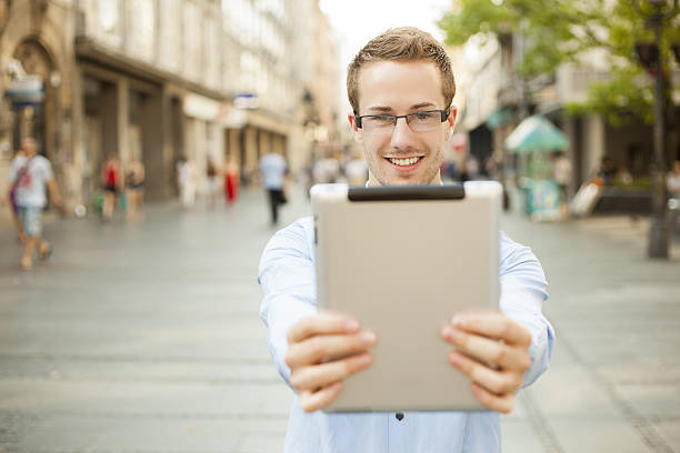 istock Smiling man hold tablet computer on urban street 155652621