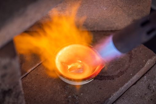 Welder flame at jeweler workshop melting silver close-up