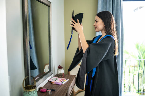 Young woman graduate getting ready looking at mirror at home