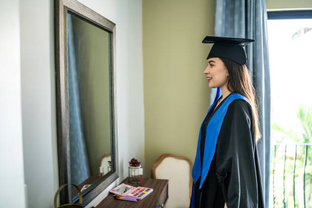 istock Young woman graduate getting ready looking at mirror at home 1556527017