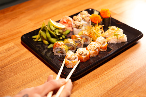 Hand holding sushi with chopsticks