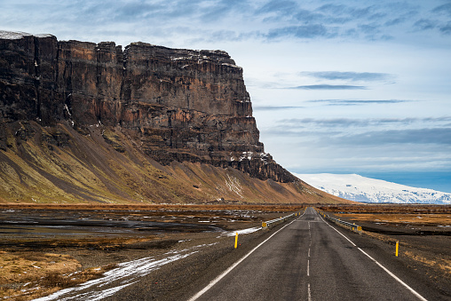 Empty Route 1 Country Road under overcast skyscape along mountain range through volcanic landscape in Southern Iceland. Vik, Iceland, Northern Europe, Nordic Countries.