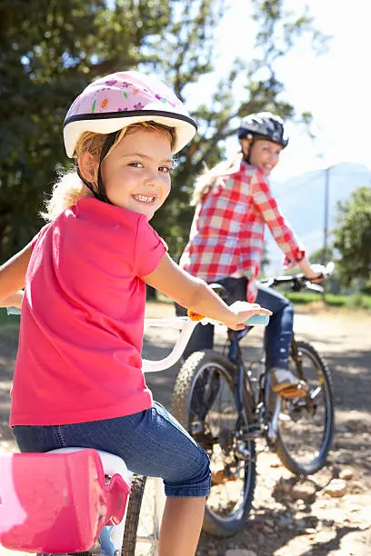 Little girl on country bike ride with mom wearing safety helmets