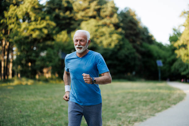 istock Sporty senior man jogging in nature park 1556567315