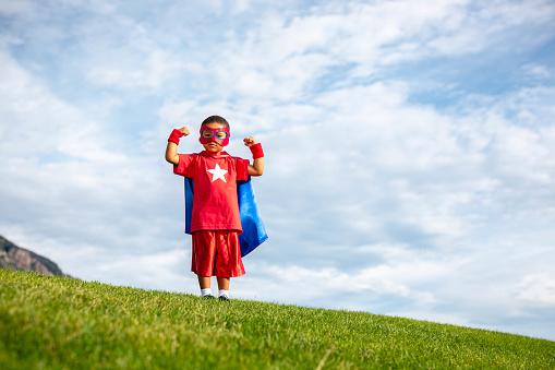 Young boy dressed as a superhero standing on grass. He is ready to protect the world from mayhem. Utah, USA.