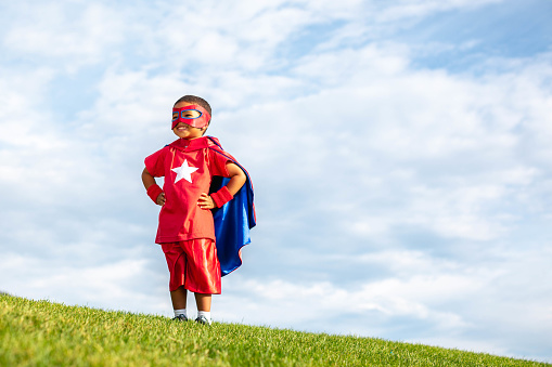 Young boy dressed as a superhero standing on grass. He is ready to protect the world from mayhem. Utah, USA.
