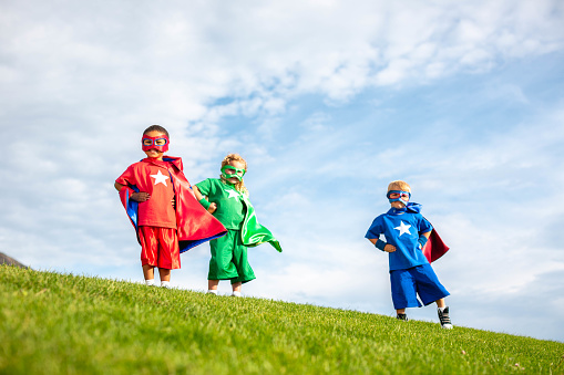 Two boys and a girl dressed as superheroes in masks and capes are ready to save the planet from peril. Utah, USA.