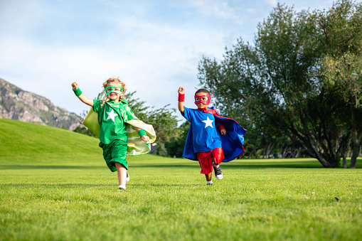 A boy and girl pair, dressed as superheroes, are running and ready to save the world.