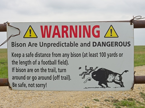 Strong City Kansas - USA, May 17, 2023. Warning sign about bison when going past the electric fence gate at Tallgrass Prairie Preserve.