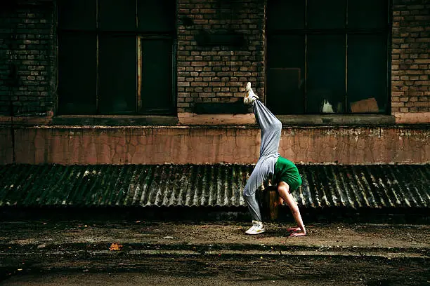 Young girl dancing against grunge wall.