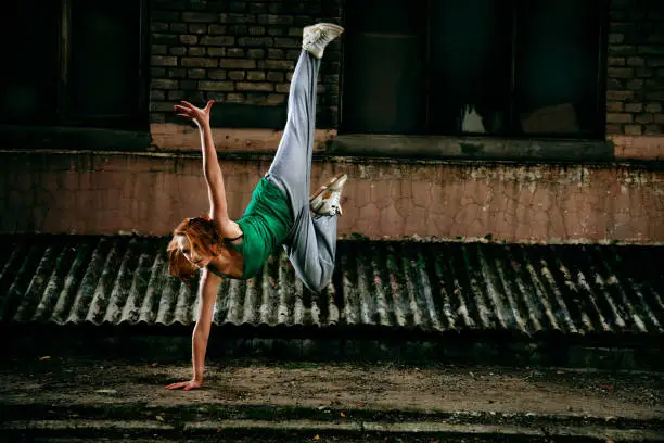 Young girl dancing against grunge wall.