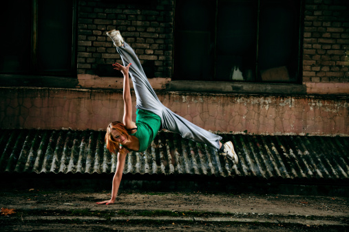 Young girl dancing against grunge wall.