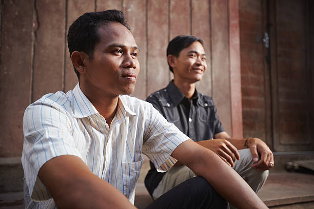 Two young Asian men smiling Two male cambodian friends sitting and looking away cambodian ethnicity stock pictures, royalty-free photos & images