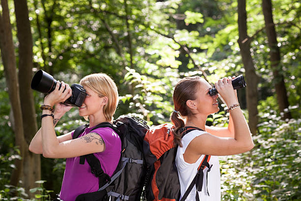 istock two women hiking in forest and looking with binoculars 155675034