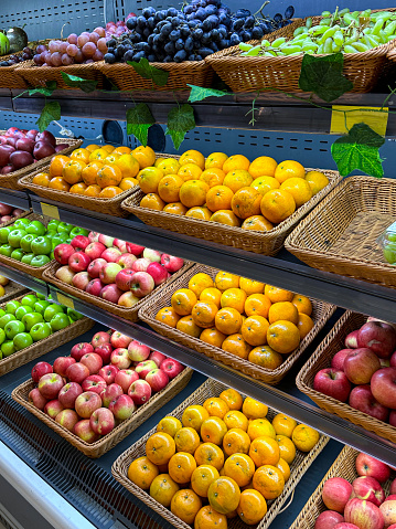 Stock photo showing interior of a supermarket with shelving rack of wicker baskets containing fresh fruit produce.