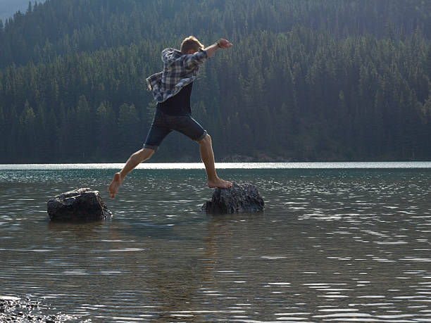 istock A man jumping bewtween boulders in a mountain lake 155676998