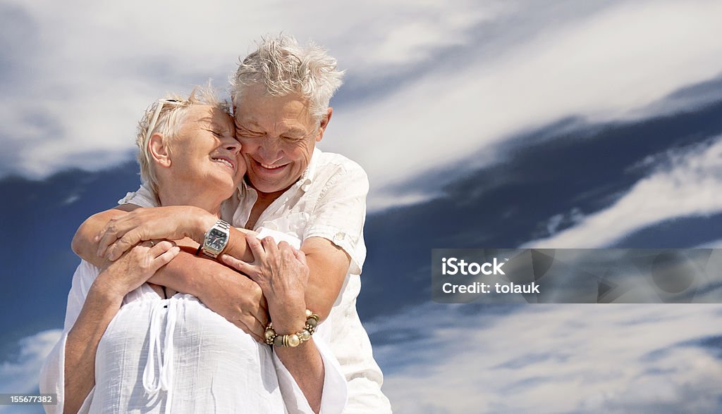 Felice coppia senior adottare contro il cielo - Foto stock royalty-free di 70-79 anni