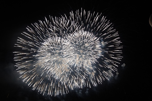 A gorgeous view of white fireworks twinkling in the dark starless sky
