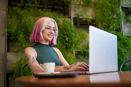 Woman with tattoo and pink hair working at cafe
