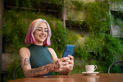 Woman with tattoo and pink hair working at cafe