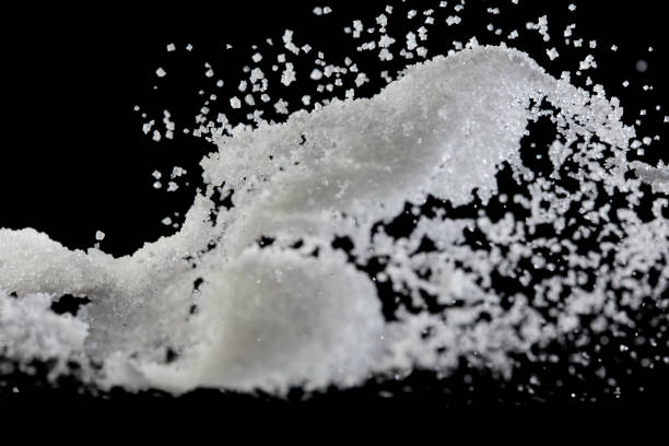 istock Salt powder pour fall in bowl, white Salt crystal cook abstract cloud fly. Ground salt splash in air, food object element design. Black background isolated selective focus blur 1556837507